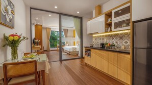 Une cuisine moderne avec des meubles en bois, un réfrigérateur en acier inoxydable et un coin repas comprenant une table et des chaises en verre.