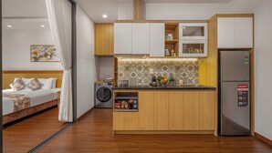 Une chambre d’hôtel compacte comprenant un coin cuisine, un lit à baldaquin et un lave-linge.