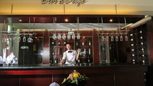 En bar med bartender, vinreol og blomsterarrangement.