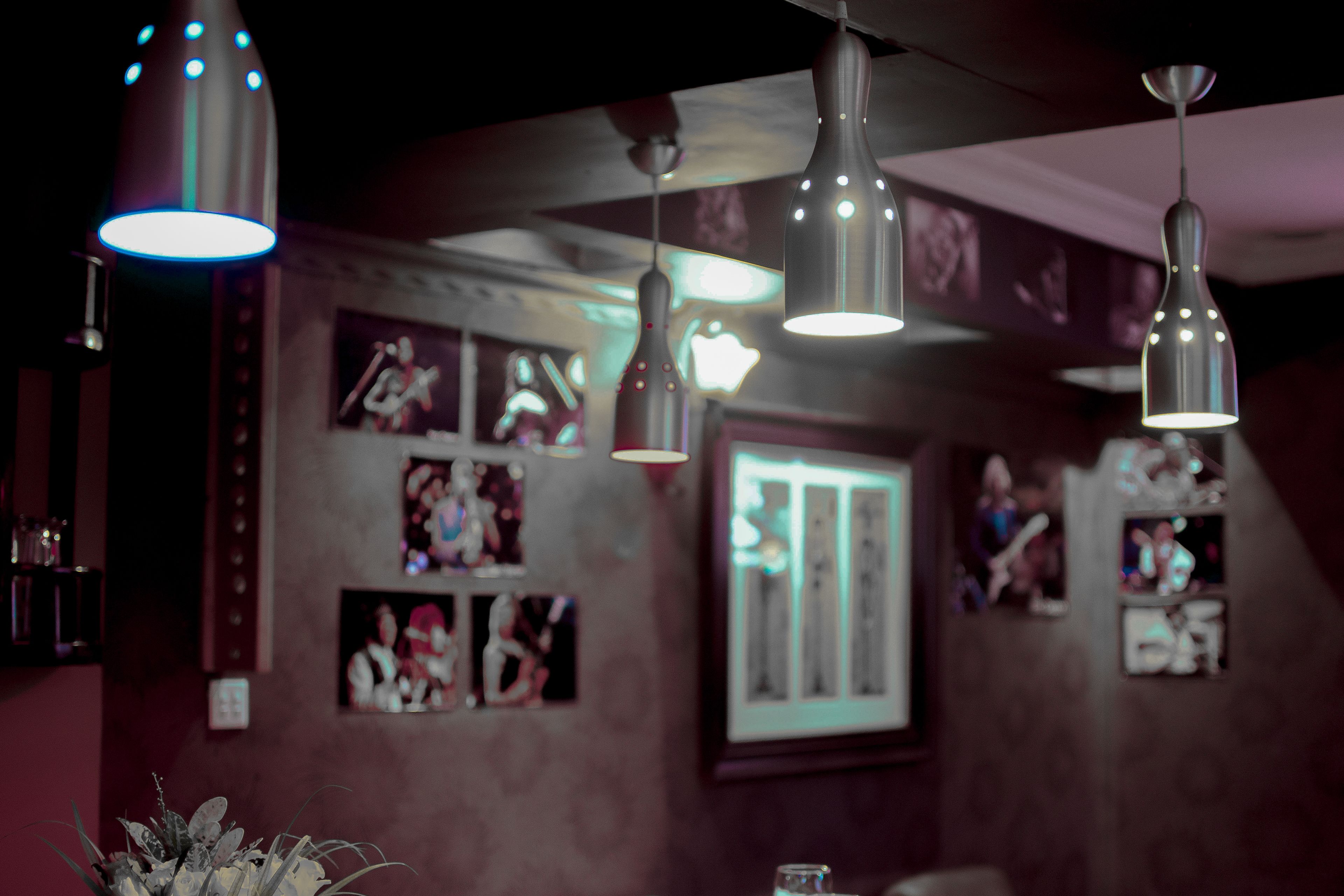 A dimly lit room with hanging pendant lights, framed pictures on the wall, and a visible window.