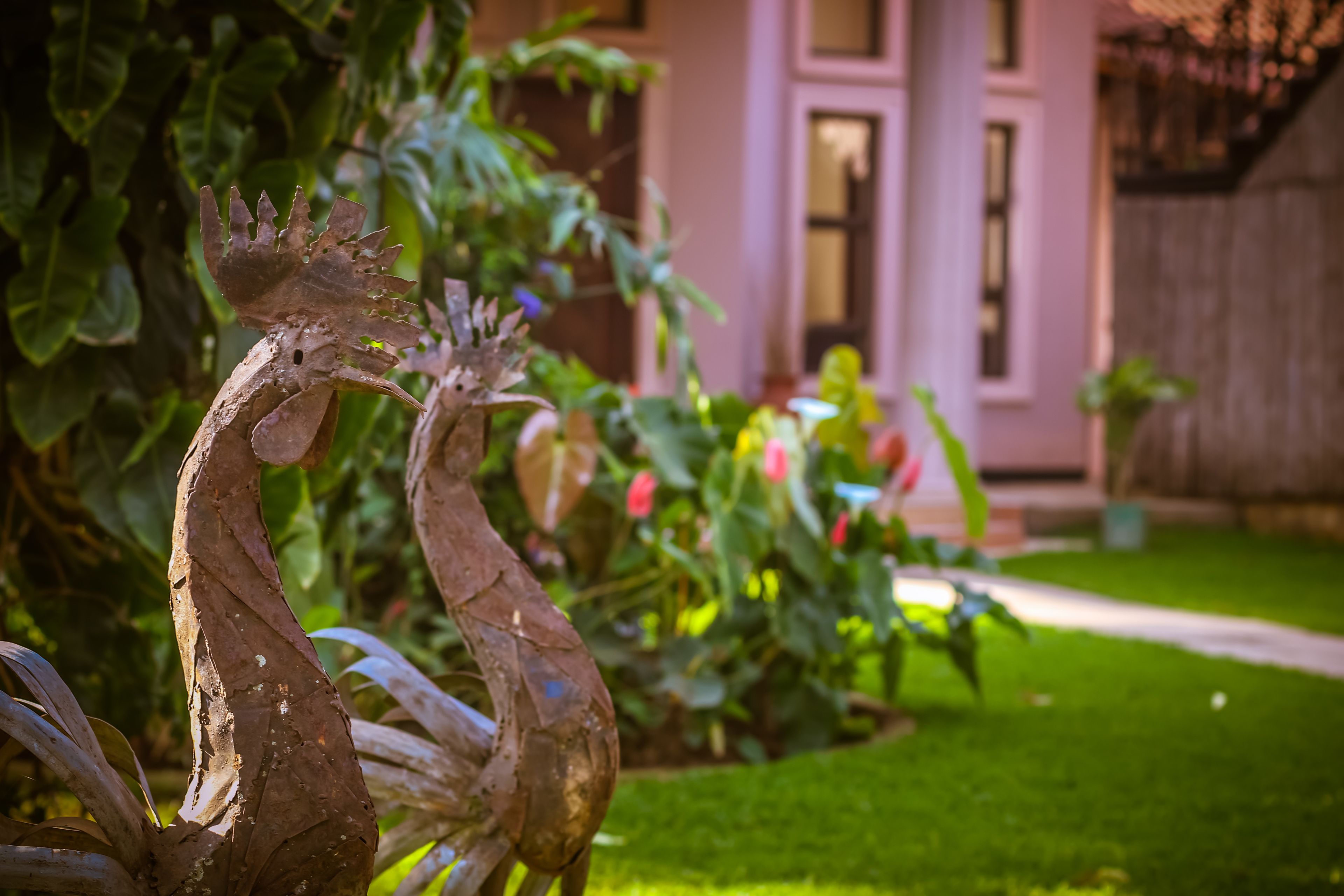 A garden with a decorative metal sculpture, lush greenery, and a building in the background.