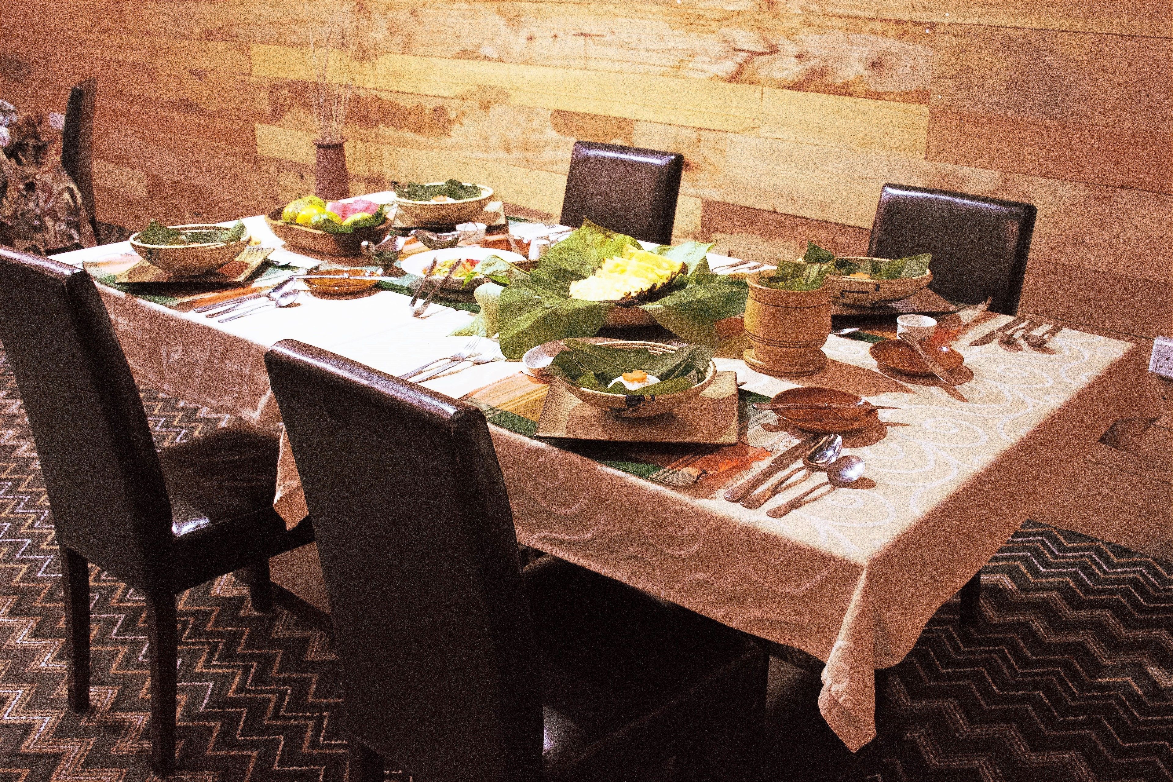 A dining table set with plates, bowls, and cutlery, surrounded by chairs.
