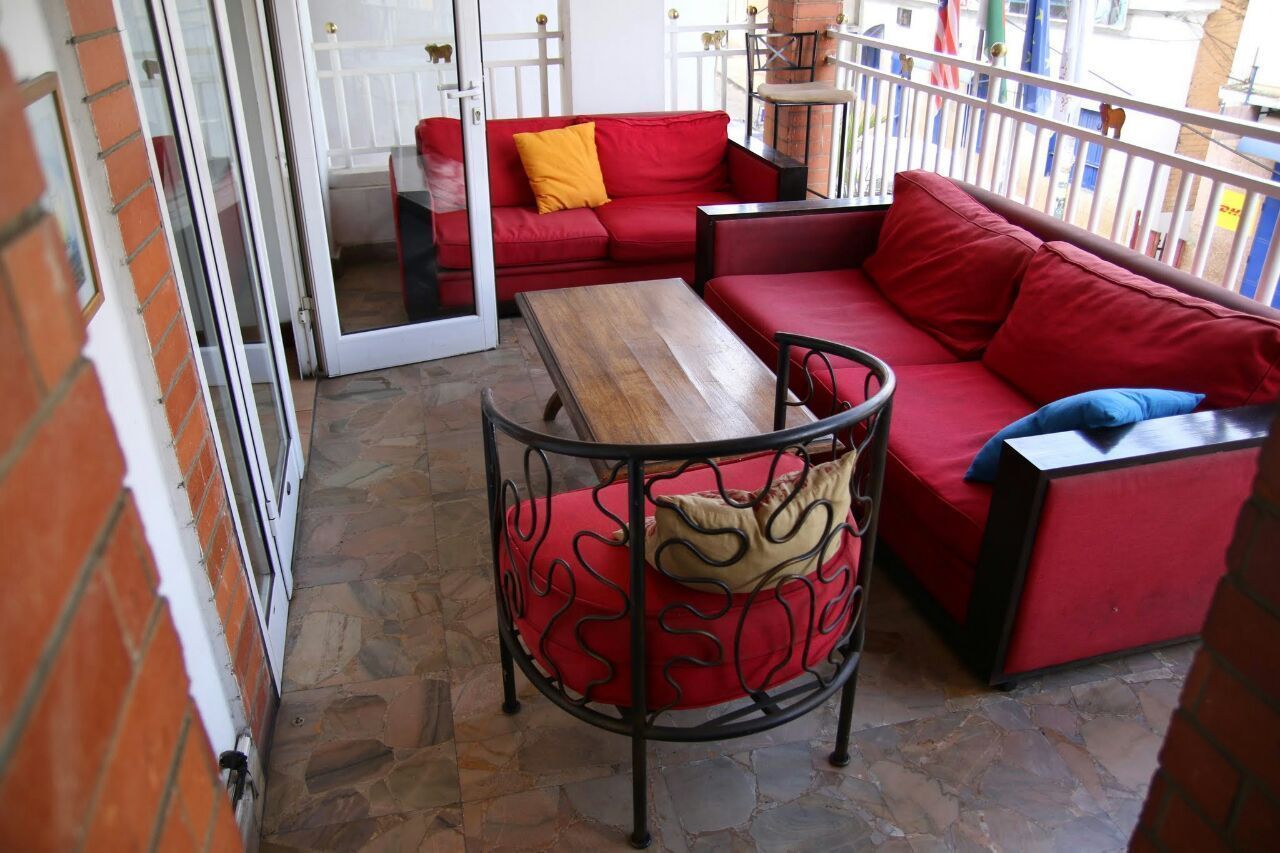A balcony with red sofas, a wooden table, and a metal chair.