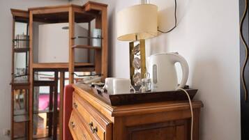 Un meuble en bois sur lequel sont posés une bouilloire, une tasse et une lampe.