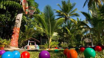 Guests can enjoy a game of basketball or relax in the gazebo amidst lush greenery and palm trees.