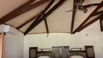 A room with two beds, a ceiling fan, and a wooden ceiling structure.