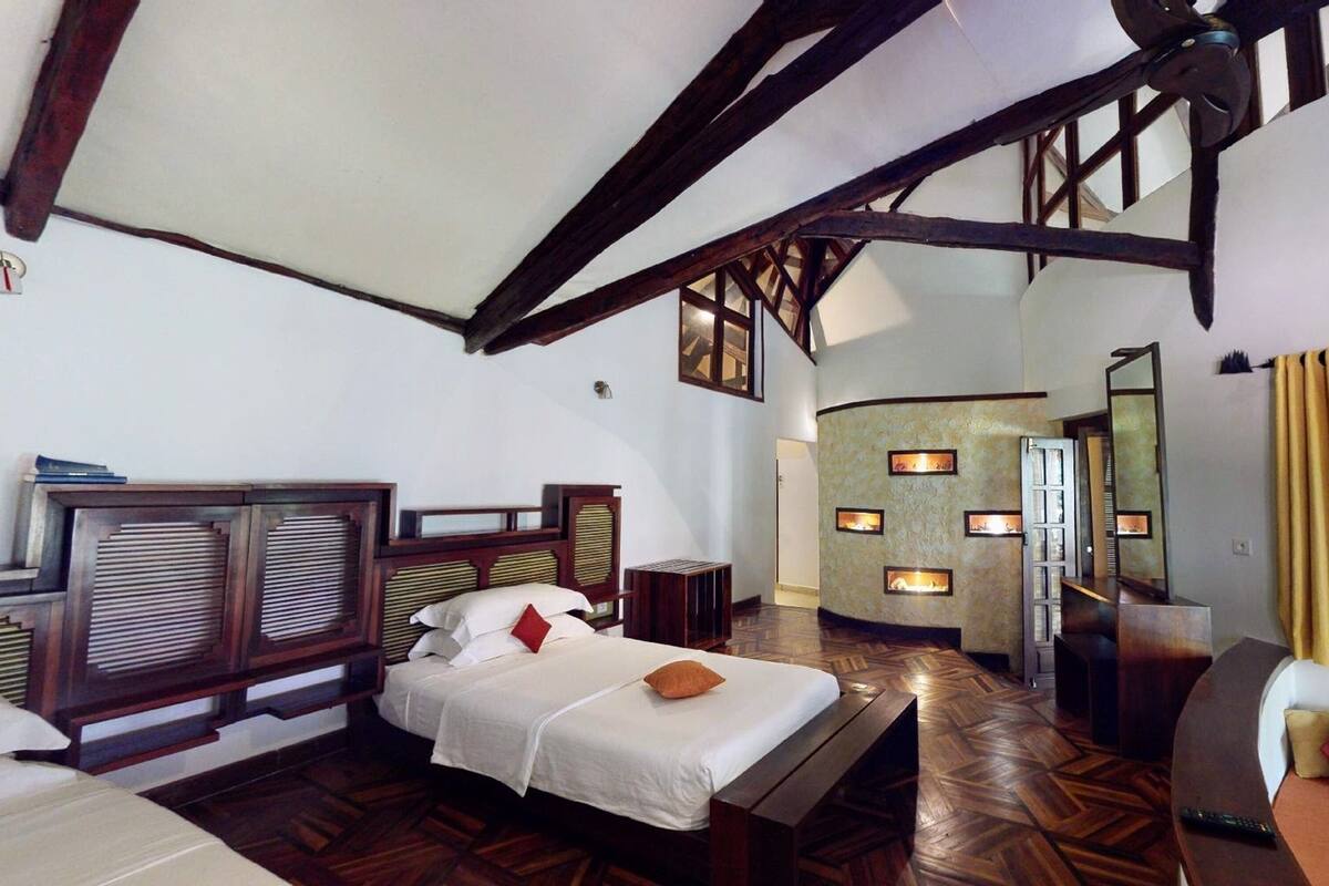 Une chambre spacieuse avec un grand lit, une tête de lit en bois et une cheminée intégrée.