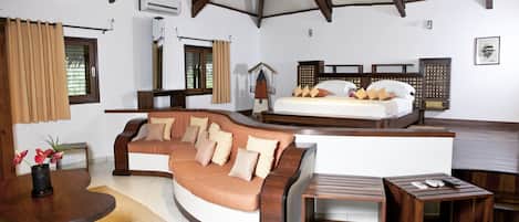 A room with a curved sofa, a bed, a small wooden table, and a bench.