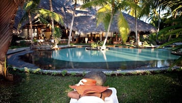 Relax by the serene pool surrounded by lush greenery and palm trees.