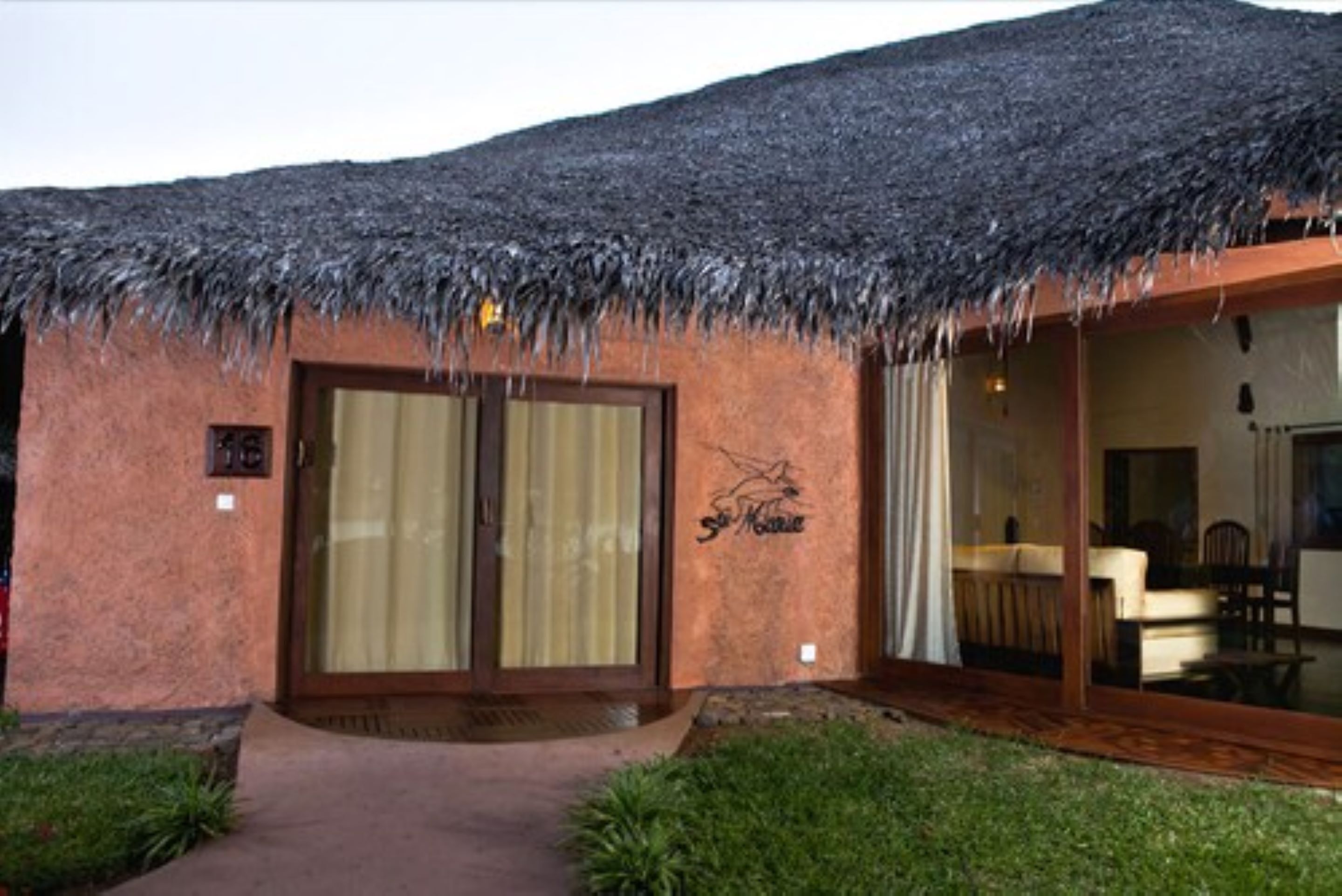 A building with a thatched roof and a large sliding glass door.