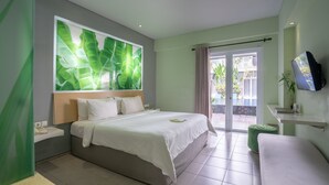 A modern hotel room with a large bed, a TV mounted on the wall, and a sliding glass door leading to a balcony. - EDEN Hotel Kuta Bali (Kuta)