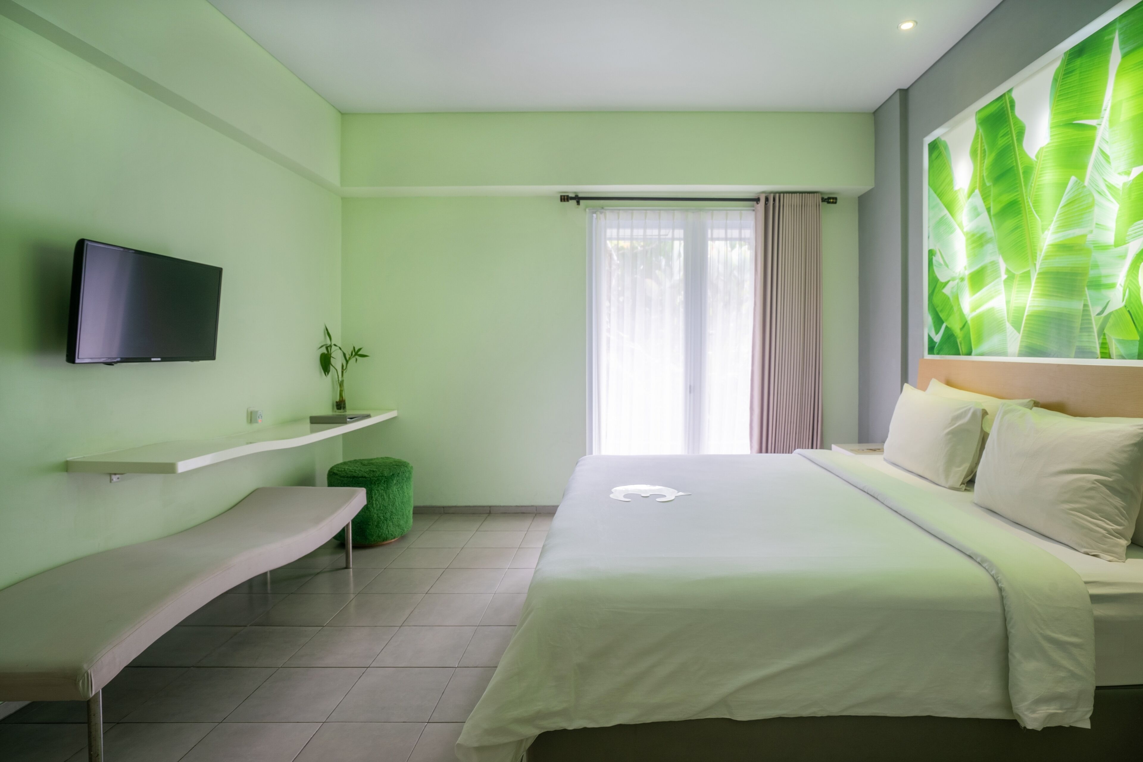 Une chambre à coucher moderne avec un lit, un banc, une télévision et une plante.