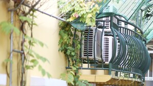 A yellow building with a green metal staircase, potted plants, and a ladder against the wall. - Golden House International Hotel (Phnom Penh)