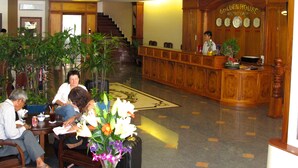 A lobby with a reception desk, wooden furniture, and potted plants. - Golden House International Hotel (Phnom Penh)