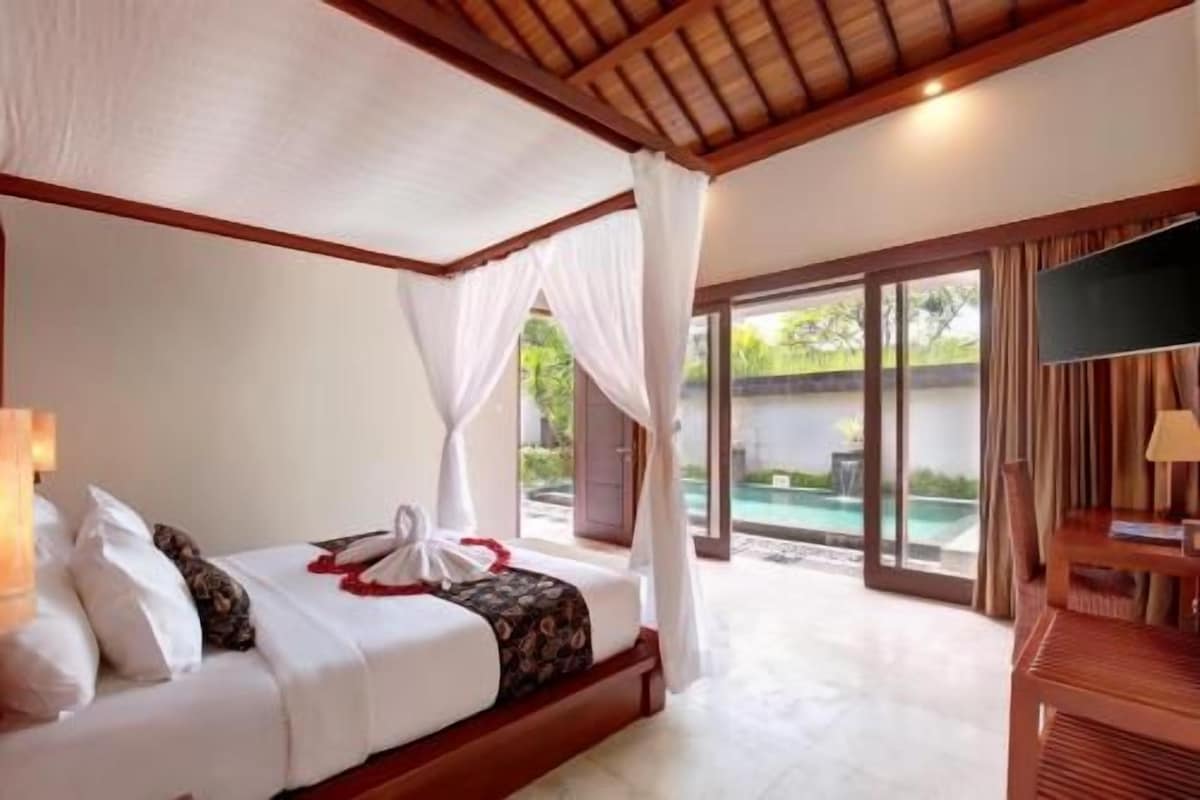 Un dormitorio con cama, televisor y vista a una piscina al aire libre.