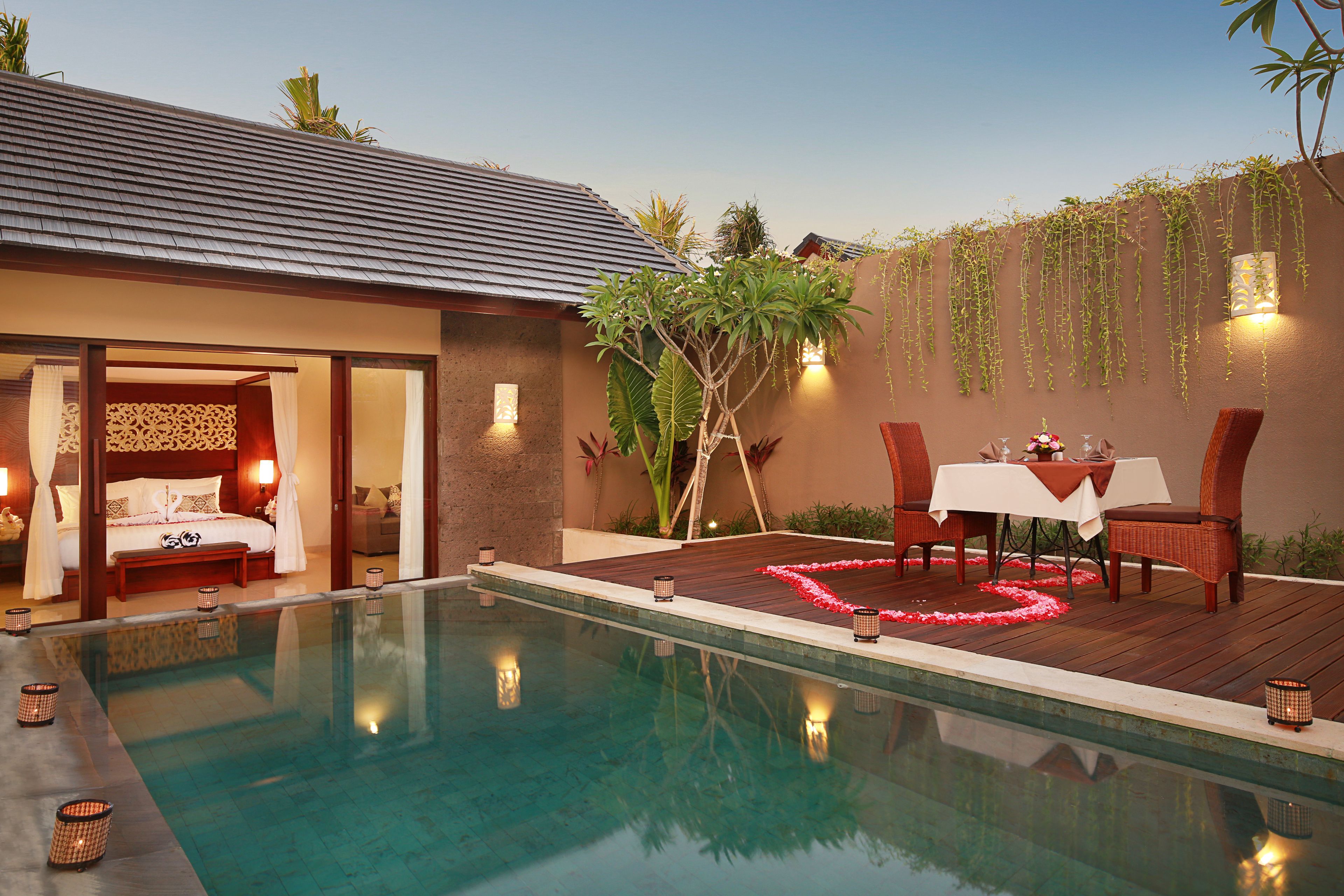 A poolside area with a bed, a dining table, and chairs.