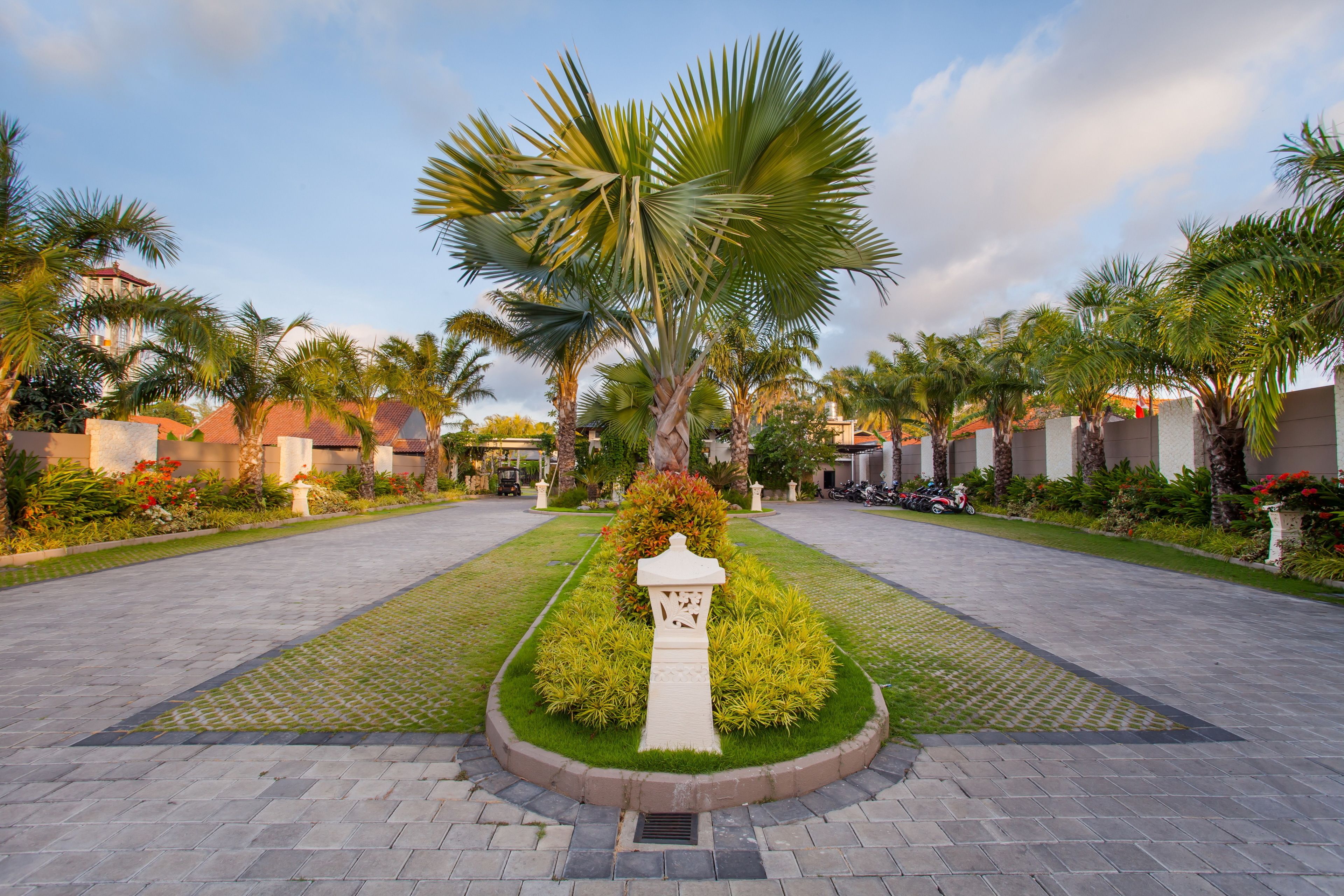 A landscaped courtyard with palm trees, a central pathway, and a decorative fountain.