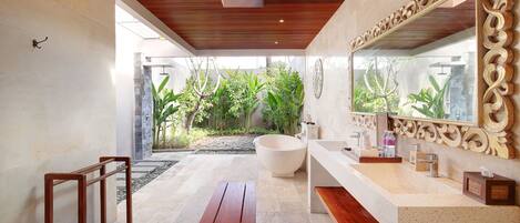 A modern bathroom with a large bathtub, a wooden bench, and a large mirror.