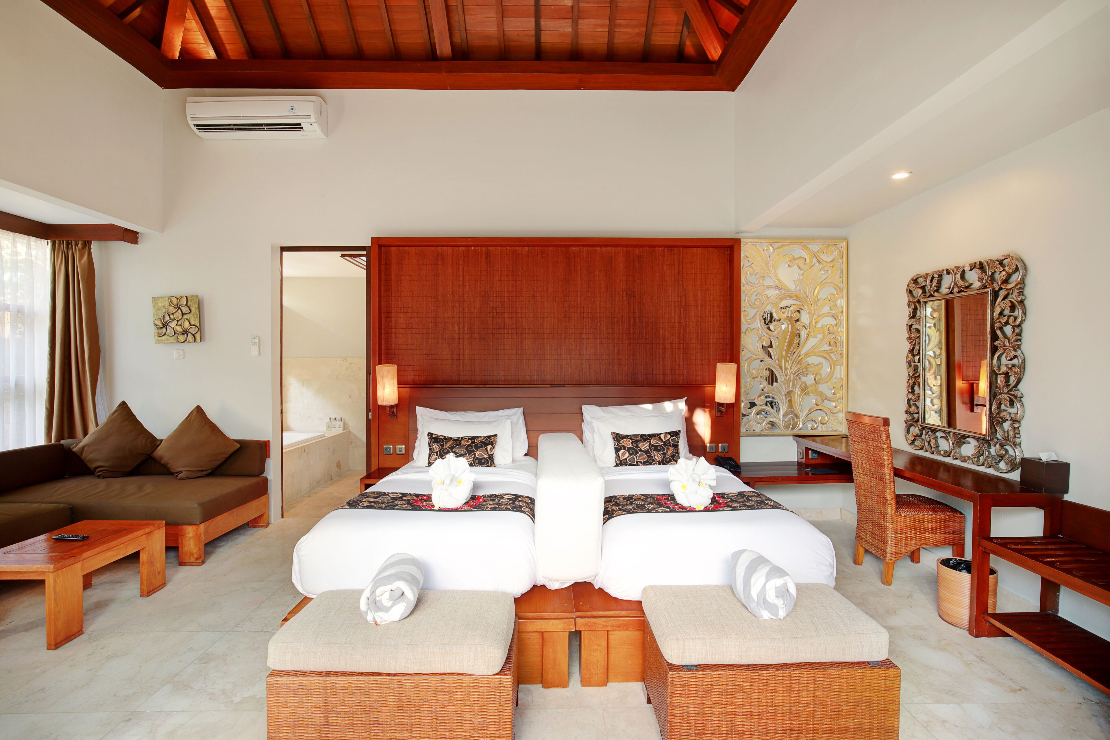 A hotel room with two beds, a sofa, a desk, and a mirror.