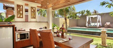 A modern kitchen with a dining area, a pool, and a gazebo.