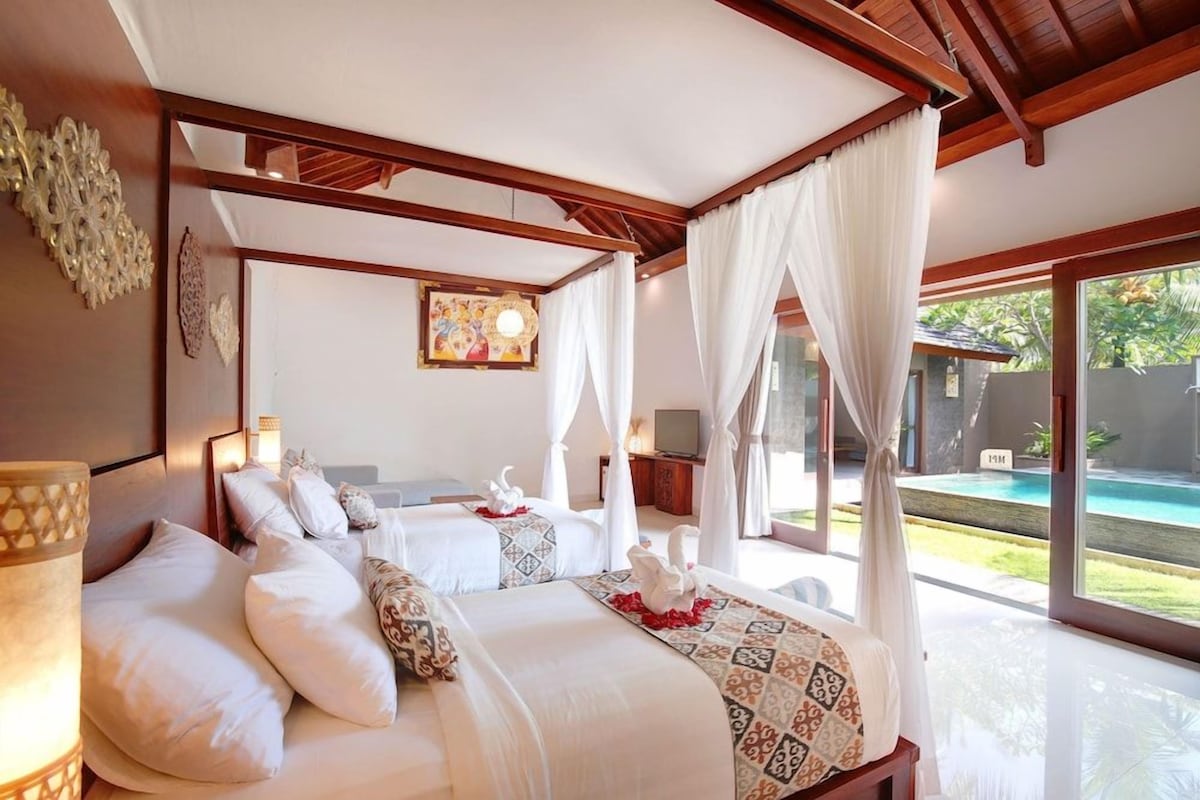 Un dormitorio con cama con dosel, televisor y vistas a una piscina.
