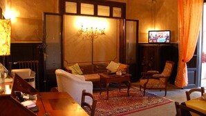 A traditional room with a sofa, armchairs, a small table, a television, and a chandelier.
