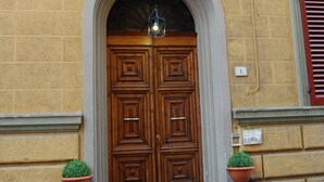 A building with a large wooden double door, a small arched entrance, and a flag above.