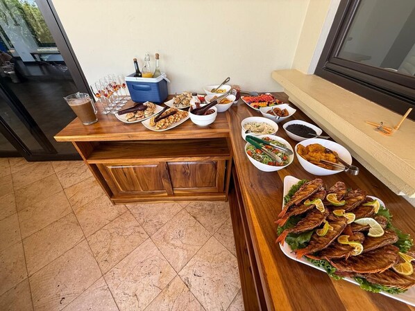 Una mesa de bufé con diversos platos, incluyendo pescado, ensaladas y bebidas.