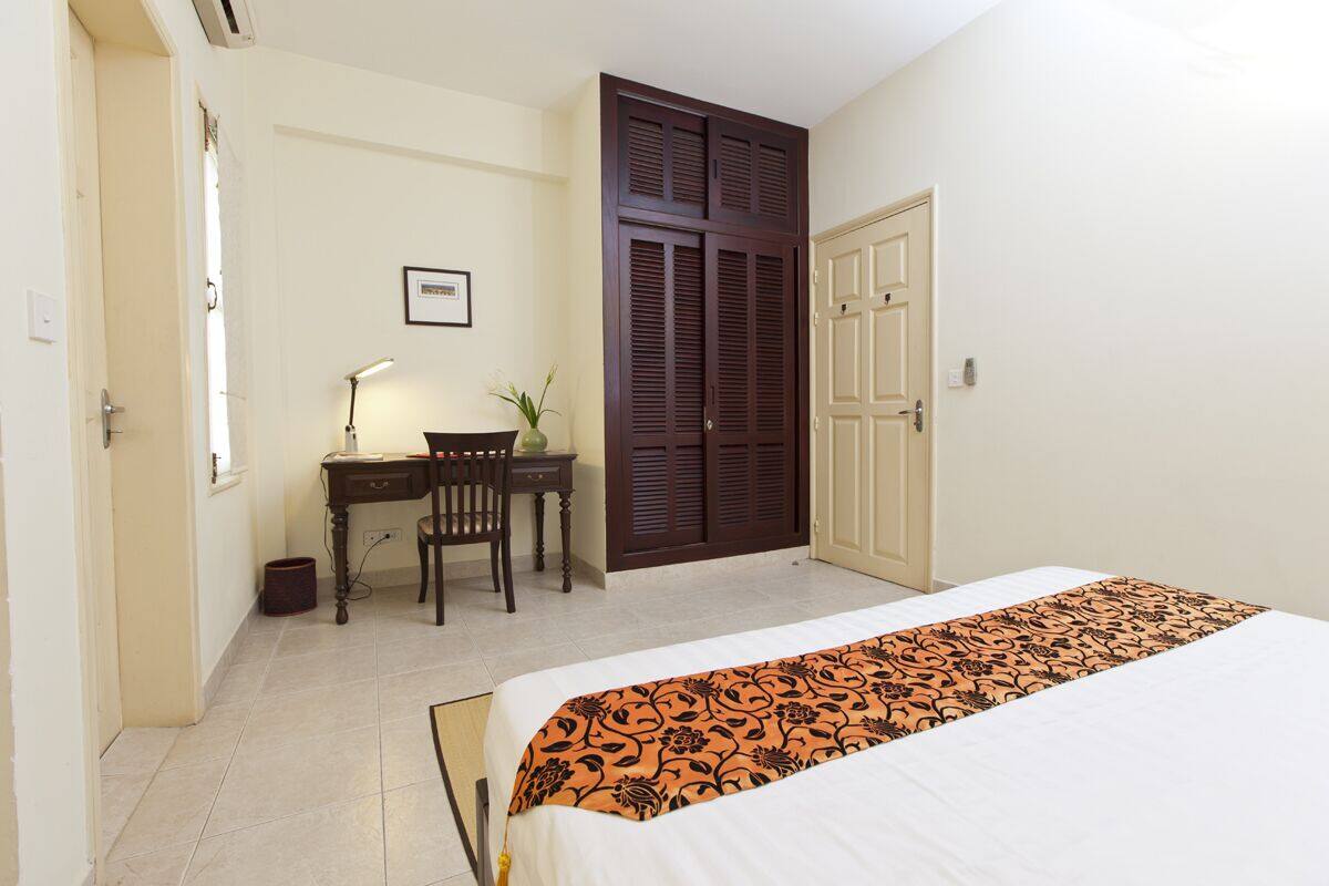A bedroom with a bed, a desk with a chair, and a wardrobe.