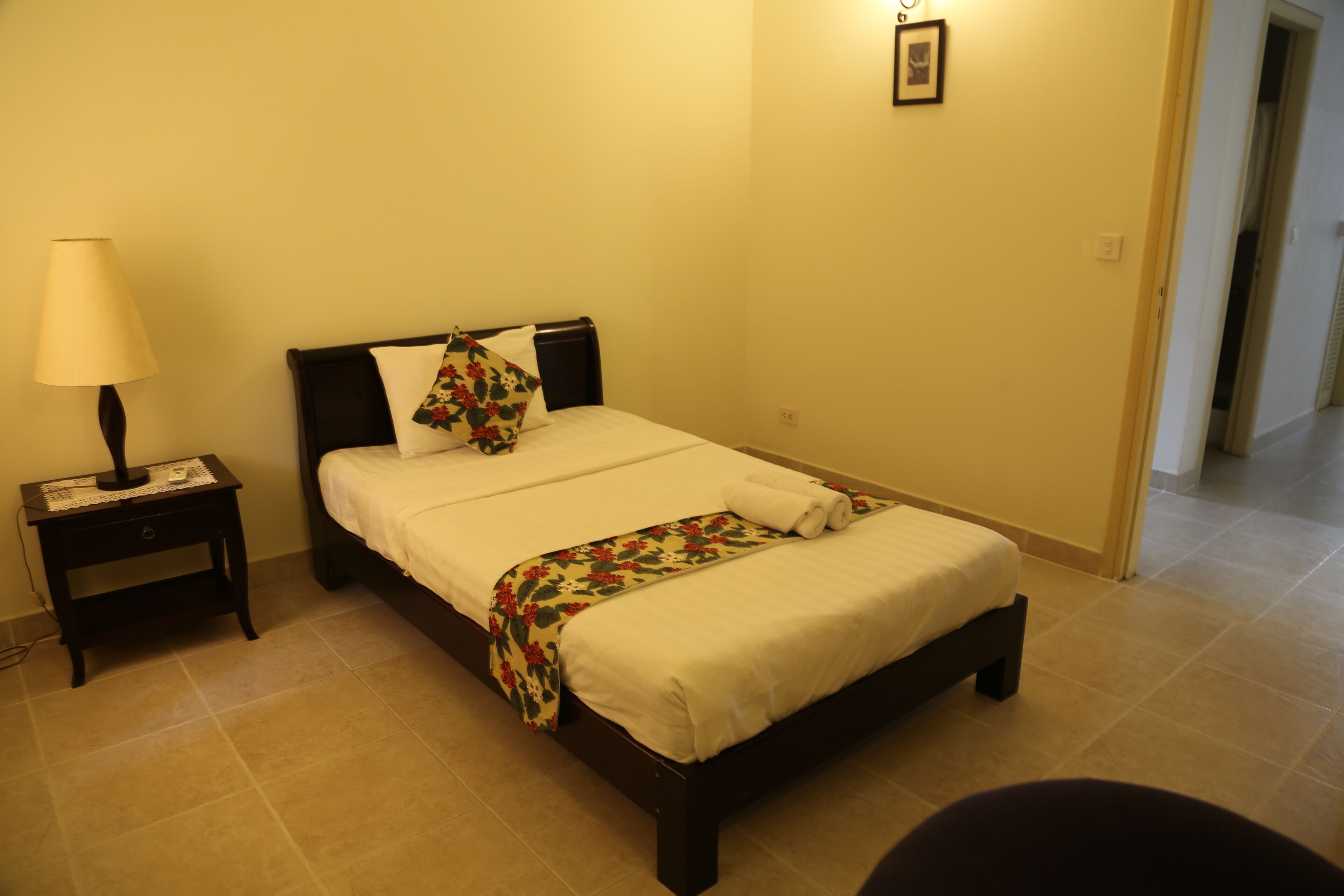A neatly made bed with floral bedding, a bedside lamp, and a small nightstand.