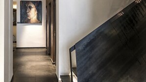 Un pasillo con piso oscuro, paredes blancas y un cuadro grande en la pared.