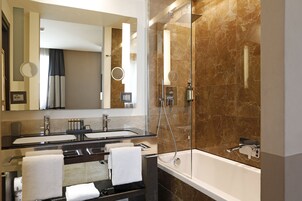 A modern bathroom with a double sink, a large mirror, a bathtub, and a glass-enclosed shower area.