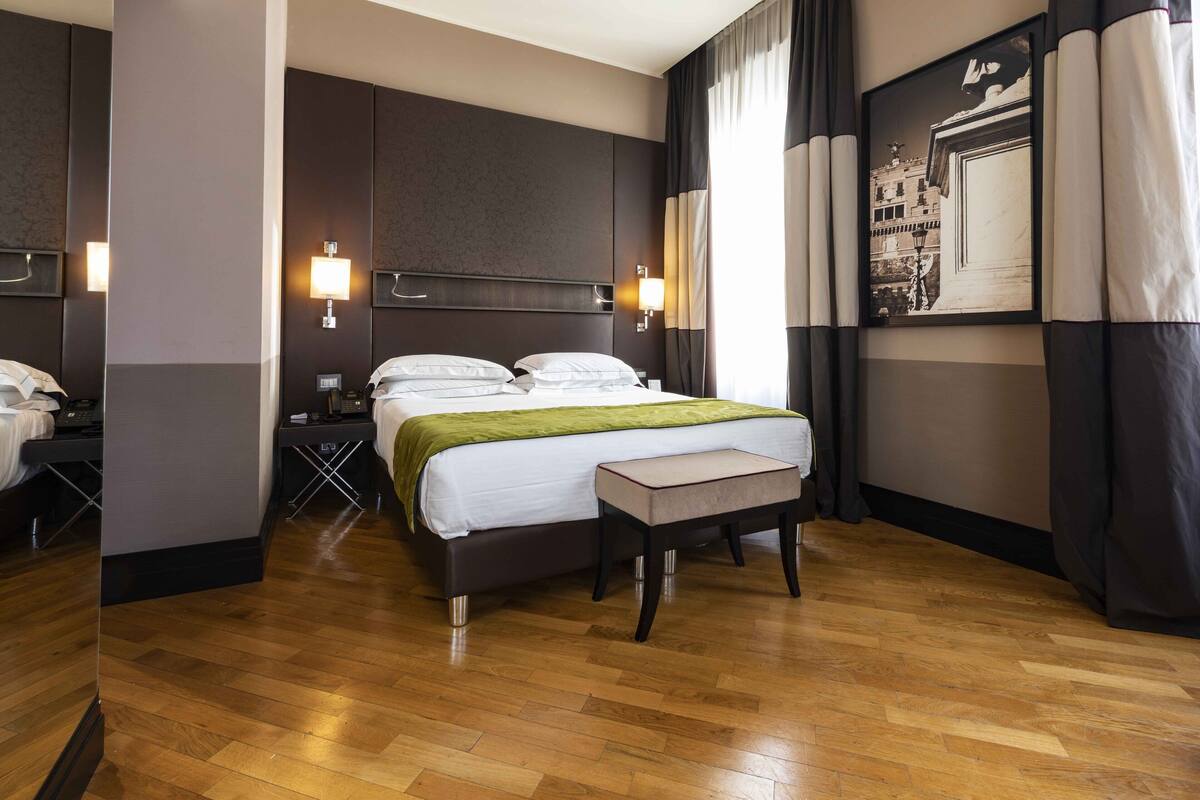 A hotel room with a large bed, bedside tables, a desk, and a chair.
