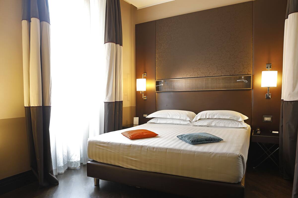 A hotel room with a large bed, two bedside tables, and a nightstand.