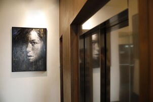 A hallway with a painting on the wall and a door leading to a room.