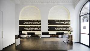 Un área de recepción moderna con dos amplios ventanales arqueados, un mostrador de recepción y una computadora portátil.