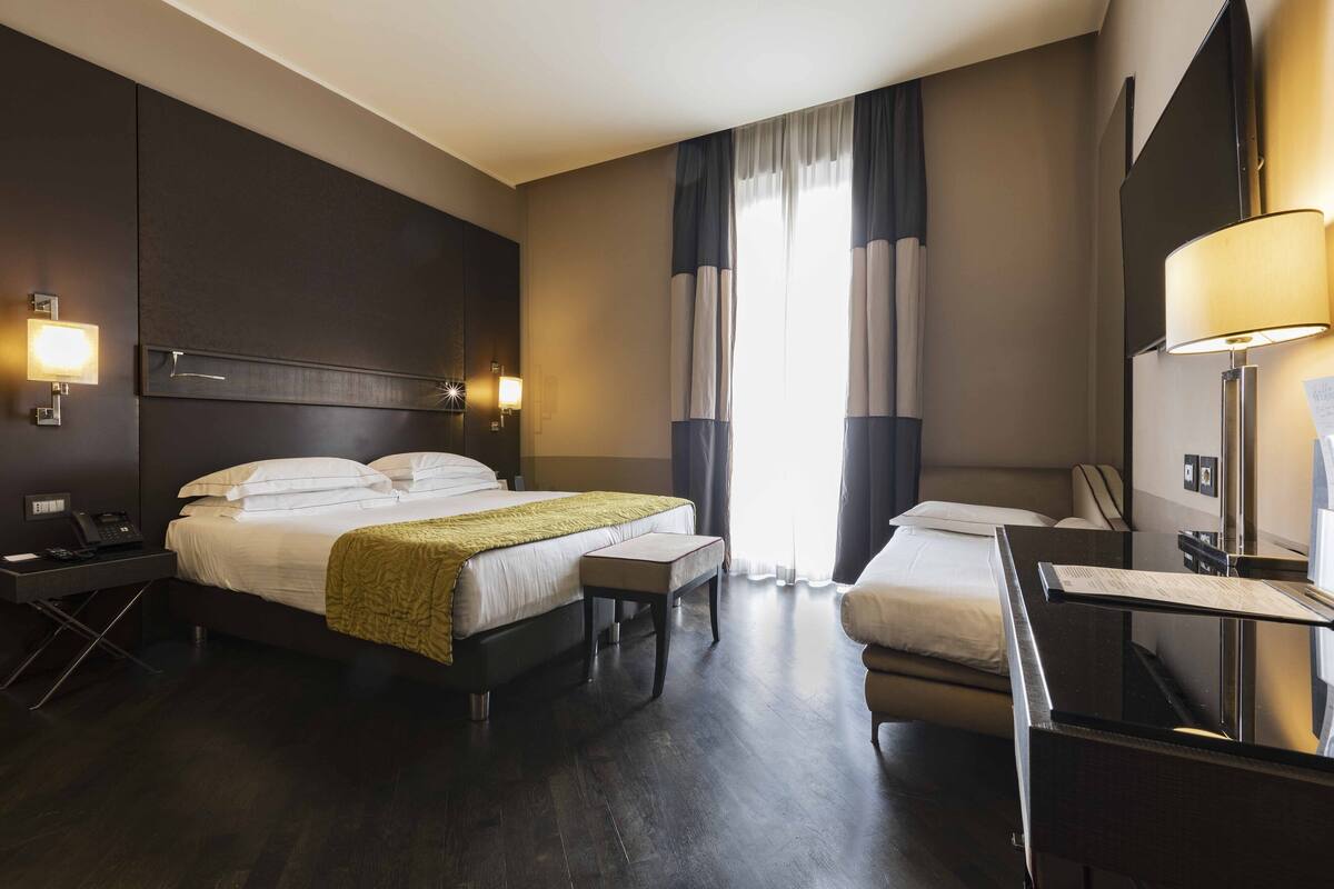 A hotel room with a large bed, bedside tables, a desk, and a chair.