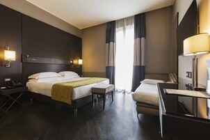 A hotel room with a large bed, bedside tables, a desk, and a chair.