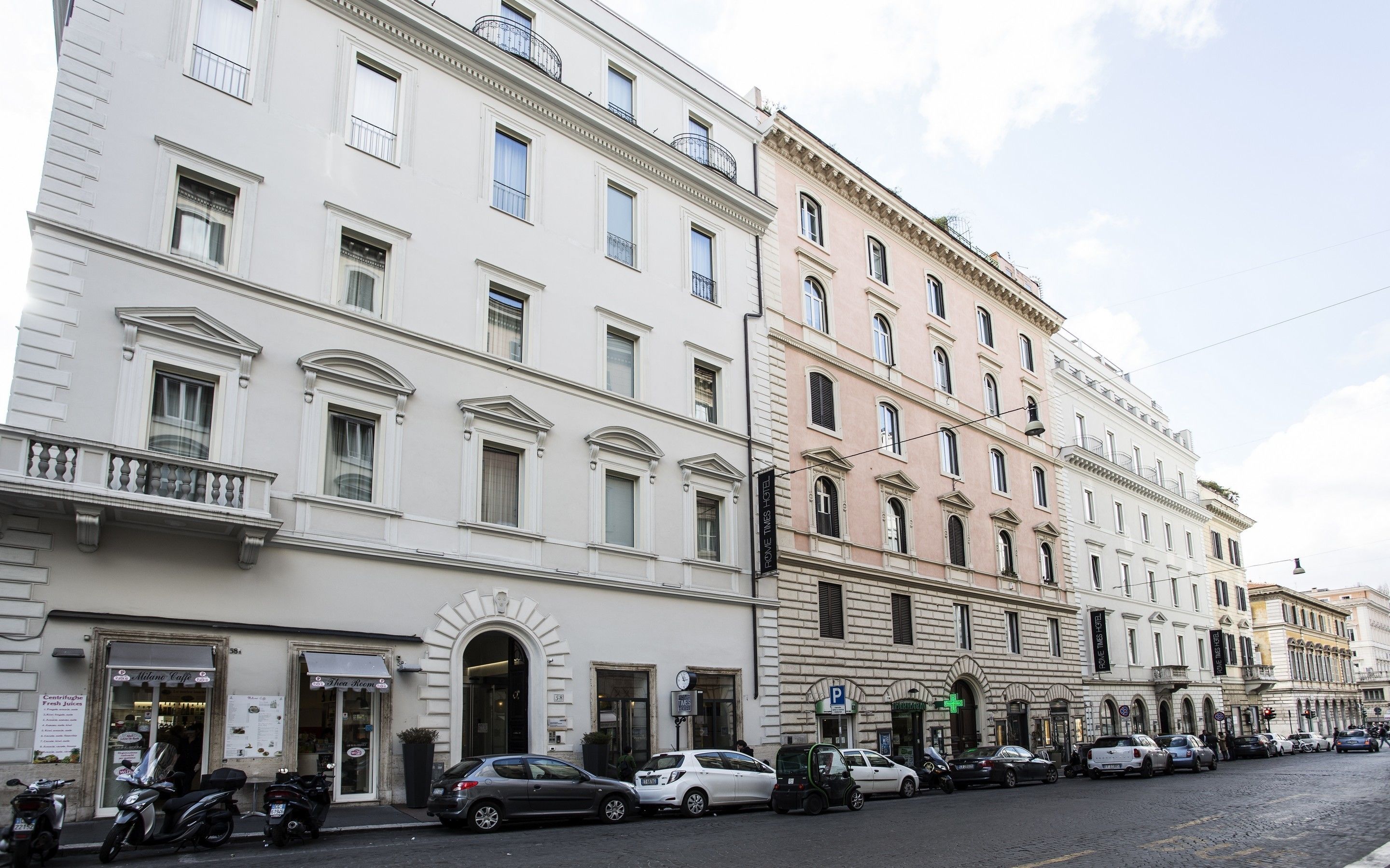 A row of historic buildings with a cafe and a pharmacy on the ground floor.