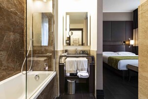 Un bagno moderno con cabina doccia in vetro, un mobile lavabo con specchio e un letto con coperta verde.