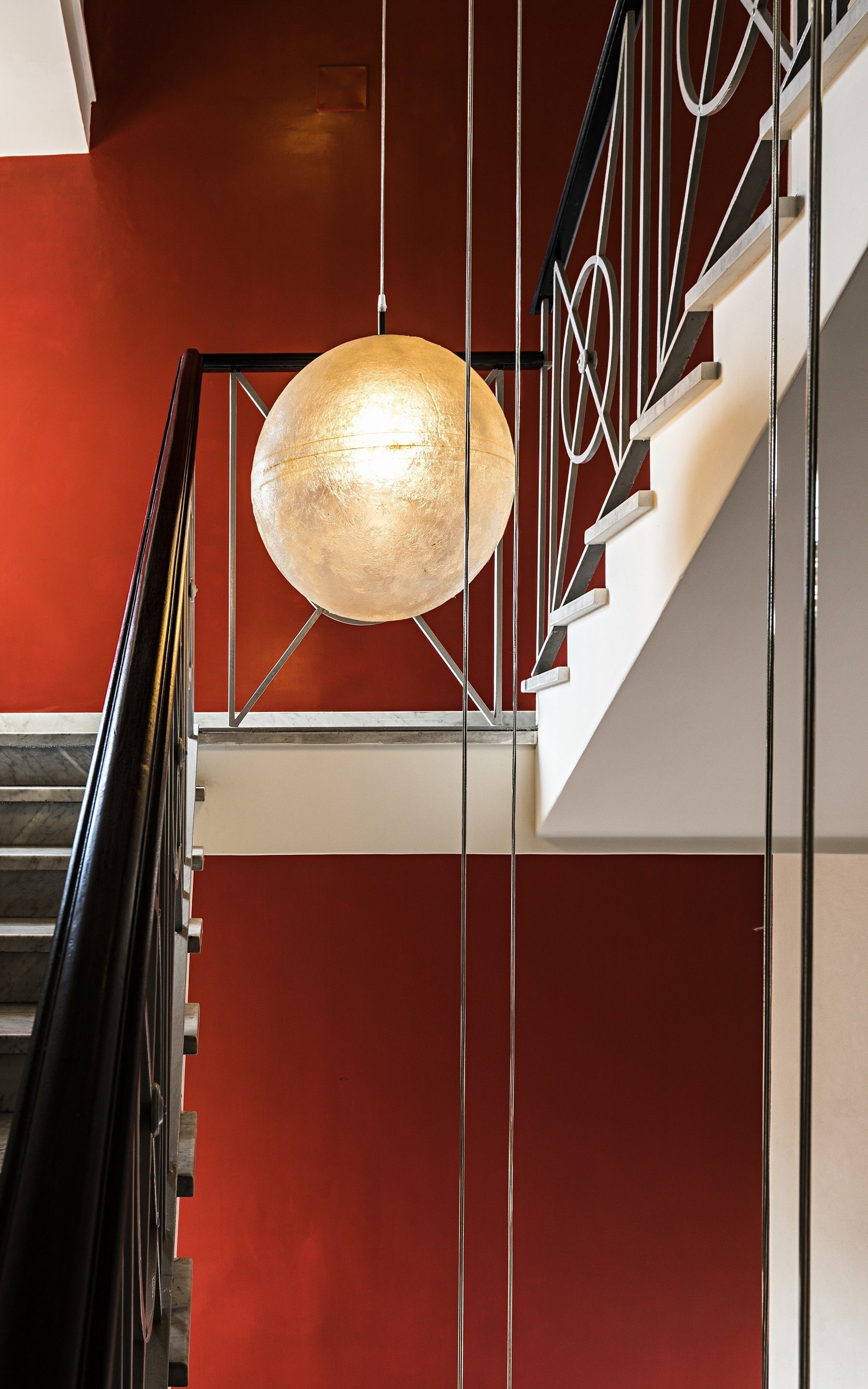 A staircase with a modern design, featuring a metal railing and a hanging pendant light.