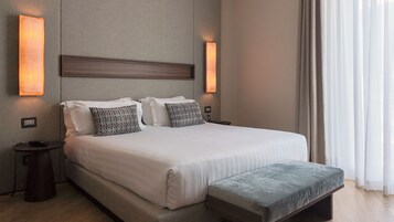 Ein Hotelzimmer mit einem großen Bett, zwei Nachttischen, einer Bank und Wandleuchten.