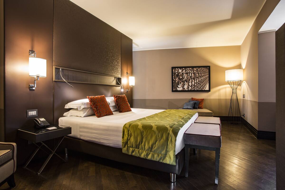 A hotel room with a large bed, bedside lamps, a desk, and a chair.