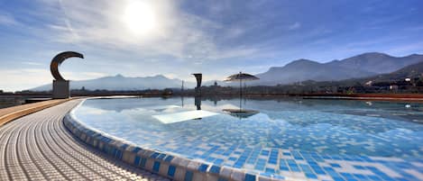 Una piscina al aire libre de temporada, sombrillas, tumbonas