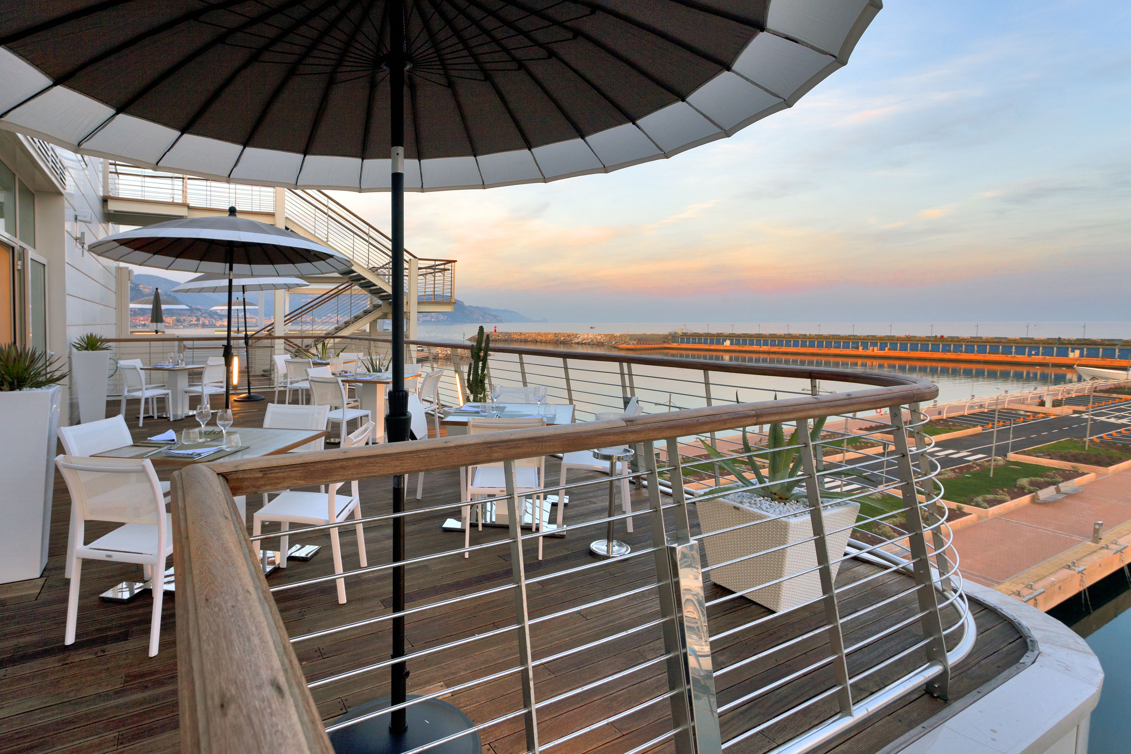 Terraza con asientos exteriores, un paraguas grande y vistas a un puente y al agua.