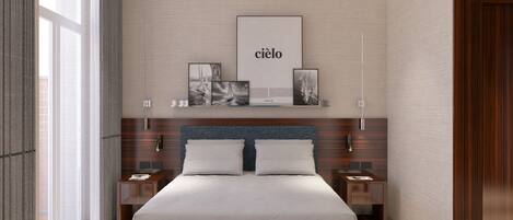 A modern bedroom with a large bed, a bench, and a wall-mounted artwork.