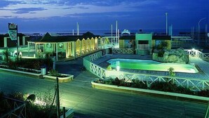 Un resort con piscina, zona cubierta y vista al océano.