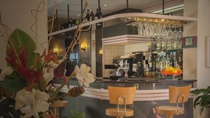 Un área de bar moderna con un mostrador curvo, dos taburetes de madera y una variedad de botellas y vasos en estantes.