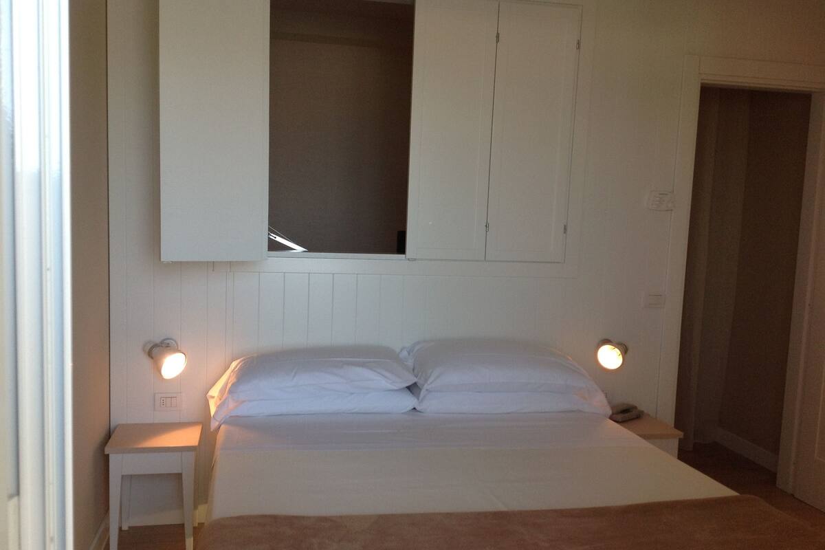 A bedroom with a bed, bedside tables, and a wardrobe.