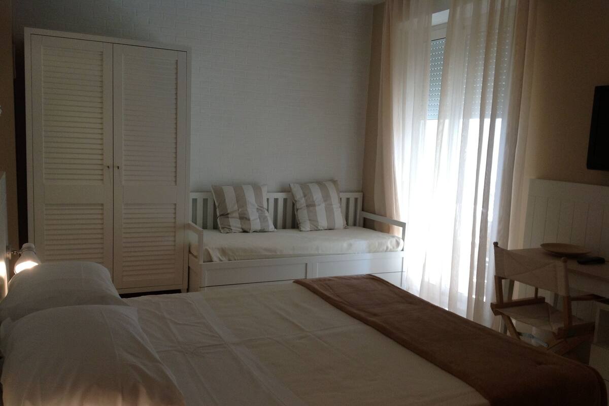 A bedroom with a bed, a desk, a chair, and a wardrobe.